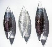 Three textured glass cocoon shapes in clear, charcoal grey and black are curated vertically in this unique wall sculpture by Julia Reimer. Image 2