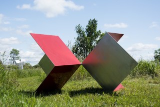 Two open steel cubes, three sides visible, sit on edge and touch at a single point.