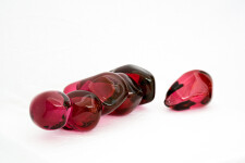 Clustered and sensuous oblong forms in translucent red glass have a smooth polished surface like the fruit that surrounds pomegranate seeds. Image 4