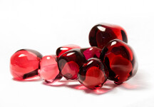Clustered and sensuous oblong forms in translucent red glass have a smooth polished surface like the fruit that surrounds pomegranate seeds. Image 4