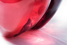 Clustered and sensuous oblong forms in translucent red glass have a smooth polished surface like the fruit that surrounds pomegranate seeds. Image 11