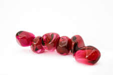 Clustered and sensuous oblong forms in translucent red glass have a smooth polished surface like the fruit that surrounds pomegranate seeds. Image 3