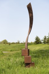 An elegantly curved column of corten steel appears to almost float in mid-air in this arresting outdoor sculpture by Claude Millette.