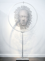 A patchwork of chrome powdercoated machine screws becomes an ethereal mask in this indoor sculpture by Dale Dunning.
