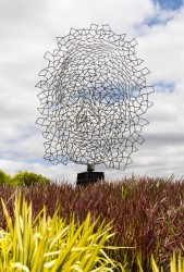 A human face emerges from the intricately designed stainless steel mesh of this intriguing sculpture.