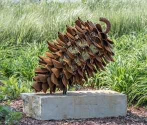 Hand forged from weathering steel Floyd Elzinga’s impressive outdoor sculpture of a pine cone is designed to house logs for a fire.
