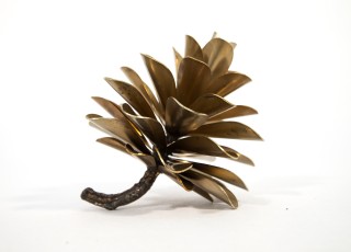 The rich golden finish of this steel pine cone by Floyd Elzinga enhances the elegance of this table top sculpture.