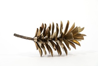 The rich silvery-golden finish of this stainless-steel pine cone by Floyd Elzinga enhances the elegance of this table top sculpture.