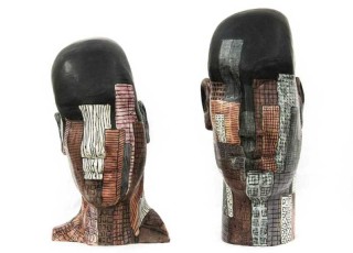 Two ceramic busts, glazed with an intricate view of a nocturnal city skyline, sit in silent communication.