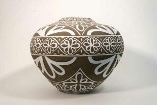 Exquisitely hand engraved white floral patterns adorn this taupe-coloured porcelain vessel by Loren Kaplan.