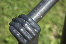 Like long arms, two vertical copper pipes topped by bronze cast hands emerge from the ground. Image 3