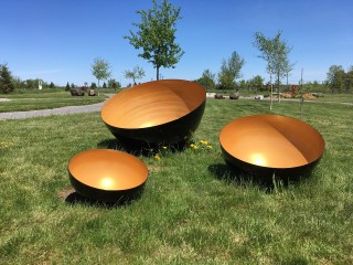 Three large stainless steel bowls, powder coated golden yellow inside and black outside, are based on Tibetan singing bowls.