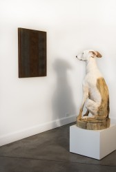 A painting on the wall and a carved figure of a dog, create this life size installation.