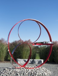 Four stainless steel rings, one side in poppy red, are curated into a elegant outdoor composition by Philippe Pallafray.