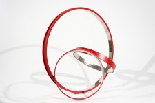 Three stainless steel rings, polished on the inside and a matte cardinal red on the exterior, are curated into an elegant, minimalist compos… Image 7