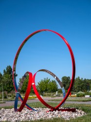 Four stainless steel rings, one side in poppy red, are curated into a elegant outdoor composition by Philippe Pallafray.