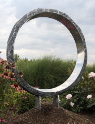 A large cast aluminum ring, polished and reflective on the inside and textured on its exterior elegantly frames the indoor space.