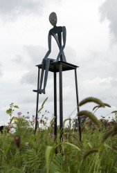 Sitting high on a metal stool, this steel figure has a bowed head, hands resting in front as if contemplating whether or not to jump.