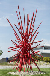 In an explosion of colour bright red painted steel poles crisscross one another in this dynamic abstract sculpture by Shayne Dark.