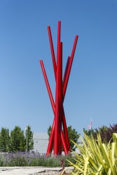Six tapered steel verticals in poppy red intersect in this soaring outdoor sculpture by Shayne Dark.