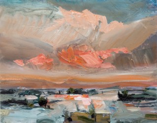 A vivid sunset in coral and turquoise with the reflection bouncing off the snow covered lake and rocks in the distance.