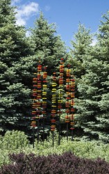 Hand blown glass rings of bright red, orange and yellow are stacked organically on seven stems in this brilliant outdoor sculpture by Susan …