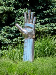 Fragments of steel are welded, like a patchwork, into an open hand in this outdoor sculpture by Susan Valyi.