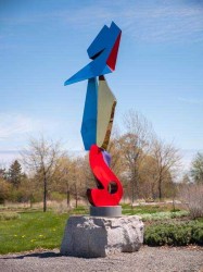 Abstract shapes in glossy red, orange, violet and blue with highlights of gold form a playful column in this outdoor sculpture by Viktor Mit…