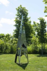 An open triangular scaffold is wrapped in a sheath of weathered steel in this intriguing outdoor sculpture by Wojtek Biczysko.