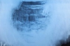 An o-ring cloud of milky blue on shimmering layers of charcoal appears to float out of the picture plane and towards the viewer. Image 2