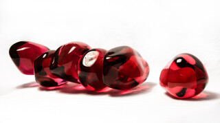Clustered and sensuous oblong forms in translucent red glass have a smooth polished surface like the fruit that surrounds pomegranate seeds.