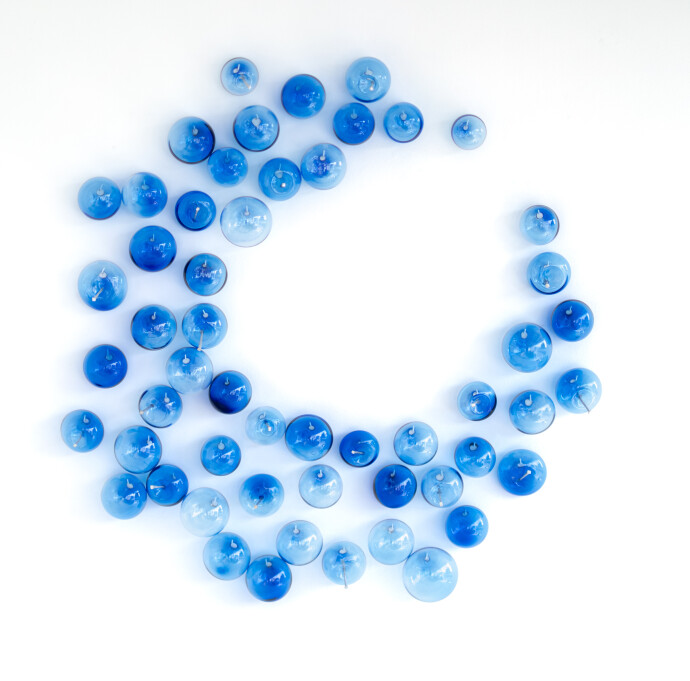This contemporary glass wall sculpture features cerulean colored bubbles.