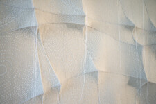 In this elegant monochromatic white tapestry by fabric artist Chung-Im Kim, finely detailed patterns swirl around the fabric. Image 4