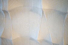 In this elegant monochromatic white tapestry by fabric artist Chung-Im Kim, finely detailed patterns swirl around the fabric. Image 7