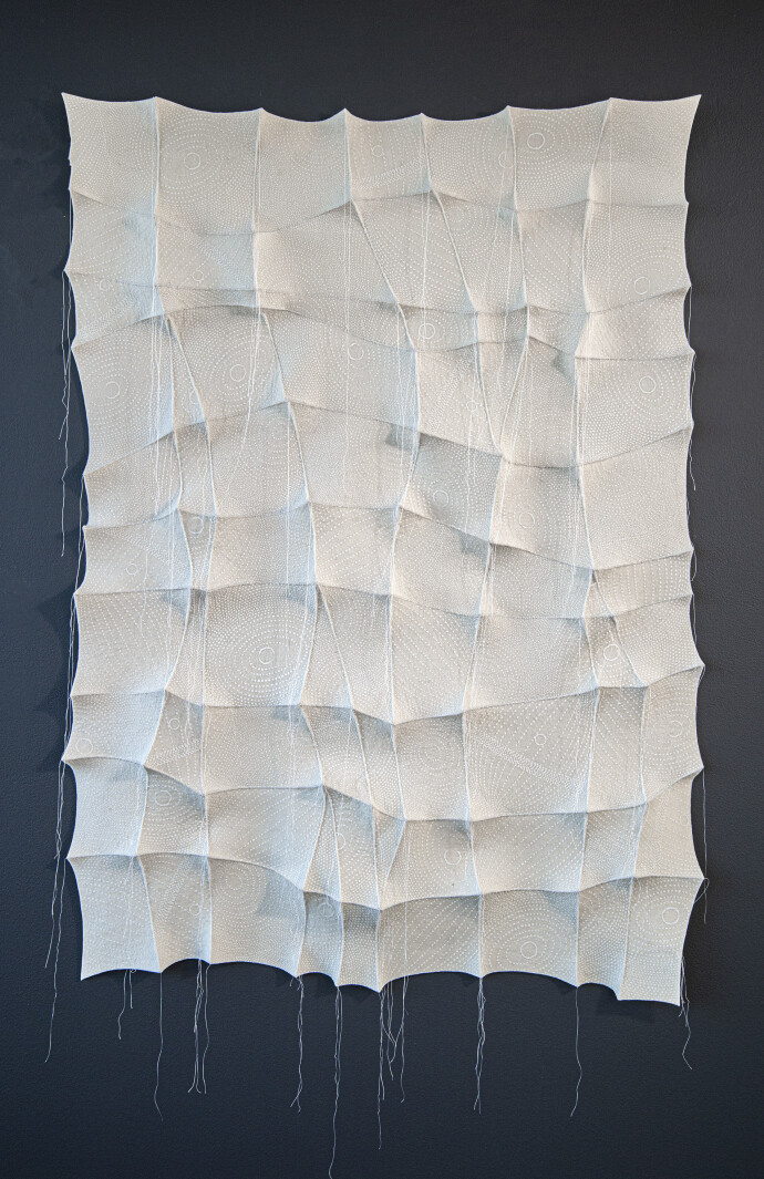 In this elegant monochromatic white tapestry by fabric artist Chung-Im Kim, finely detailed patterns swirl around the fabric.