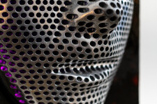 This contemporary figurative wall sculpture is a mask forged from metal lit with LED light. Image 12