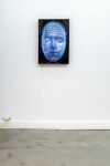 This contemporary figurative wall sculpture is a mask forged from metal lit with LED light. Image 2