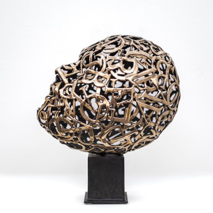 This contemporary table top sculpture is a mask forged from metal.