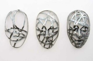 This contemporary wall sculpture is a series of three masks forged from metal.