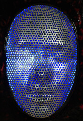 This contemporary figurative wall sculpture is a mask forged from metal lit with LED light.