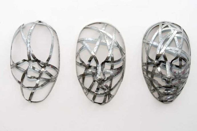 Narrow strips of aluminum are skillfully shaped in to the curves and folds of three masks in this triptych by sculptor Dale Dunning.