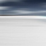 In this serene composition by Etienne Labbé, the bright white sand of a beach meets the shining aqua sea and a dramatic cloudy sky. Image 2