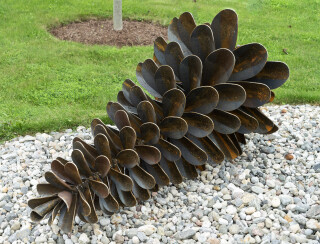 This contemporary outdoor sculpture was forged from steel; its form is inspired by nature.