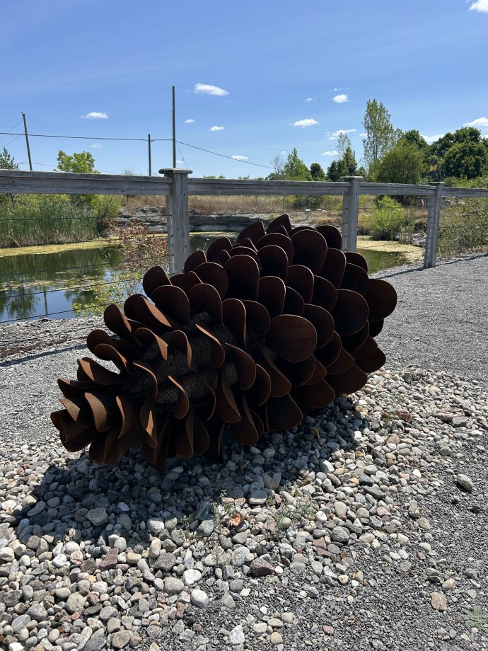 This contemporary outdoor steel sculpture of a pine cone by Floyd Elzinga is also wood-burning.