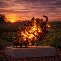 Hand forged from weathering steel Floyd Elzinga’s impressive outdoor sculpture of a pine cone is designed to house logs for a fire.