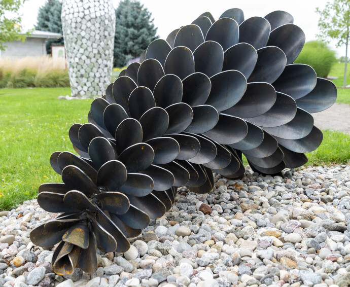 This contemporary outdoor sculpture was forged from steel; its form is inspired by nature.