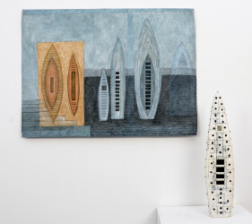 A ceramic canoe shape perforated and marked emerges from a plinth next to a tapestry of blue and light brown that repeats the vertical canoe…