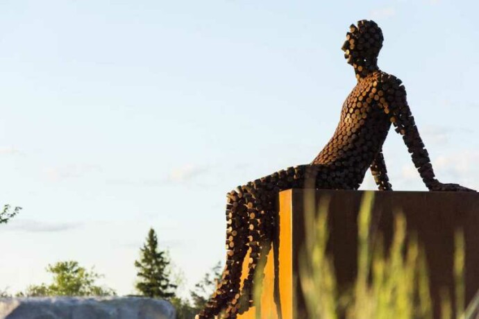 A seated figure reclines atop a steel cube in this intriguing work by Mississippi sculptor Jason Kimes.