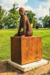 A seated female figure strikes a casual pose, body half turned in this imposing sculpture by American artist, Jason Kimes. Image 5