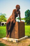 A seated female figure strikes a casual pose, body half turned in this imposing sculpture by American artist, Jason Kimes. Image 8